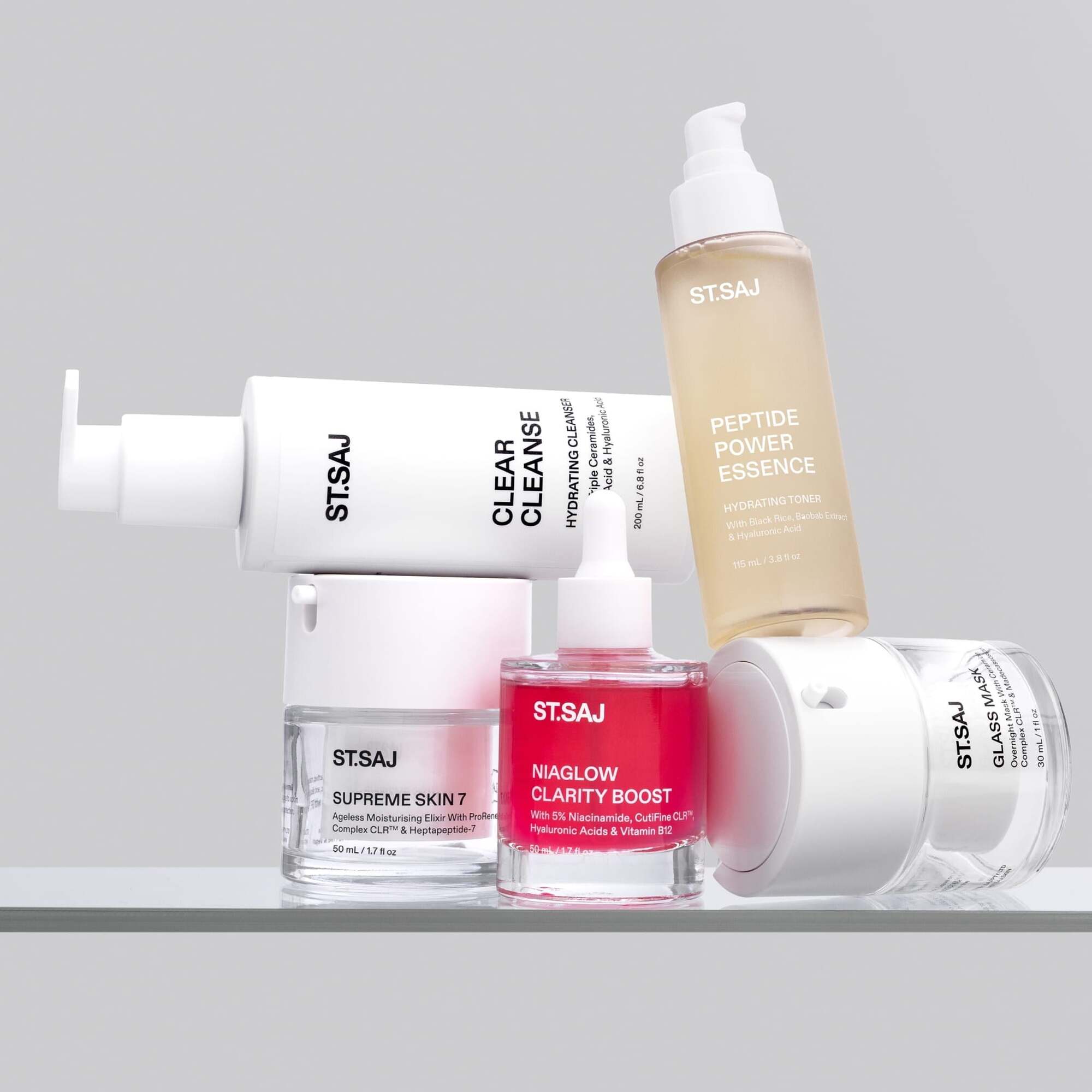 ST.SAJ Clear Skin Routine product group - Clear Cleanse, Peptide Power Essence, Supreme Skin 7, Niaglow Clarity Boost and Glass Mask on grey background.