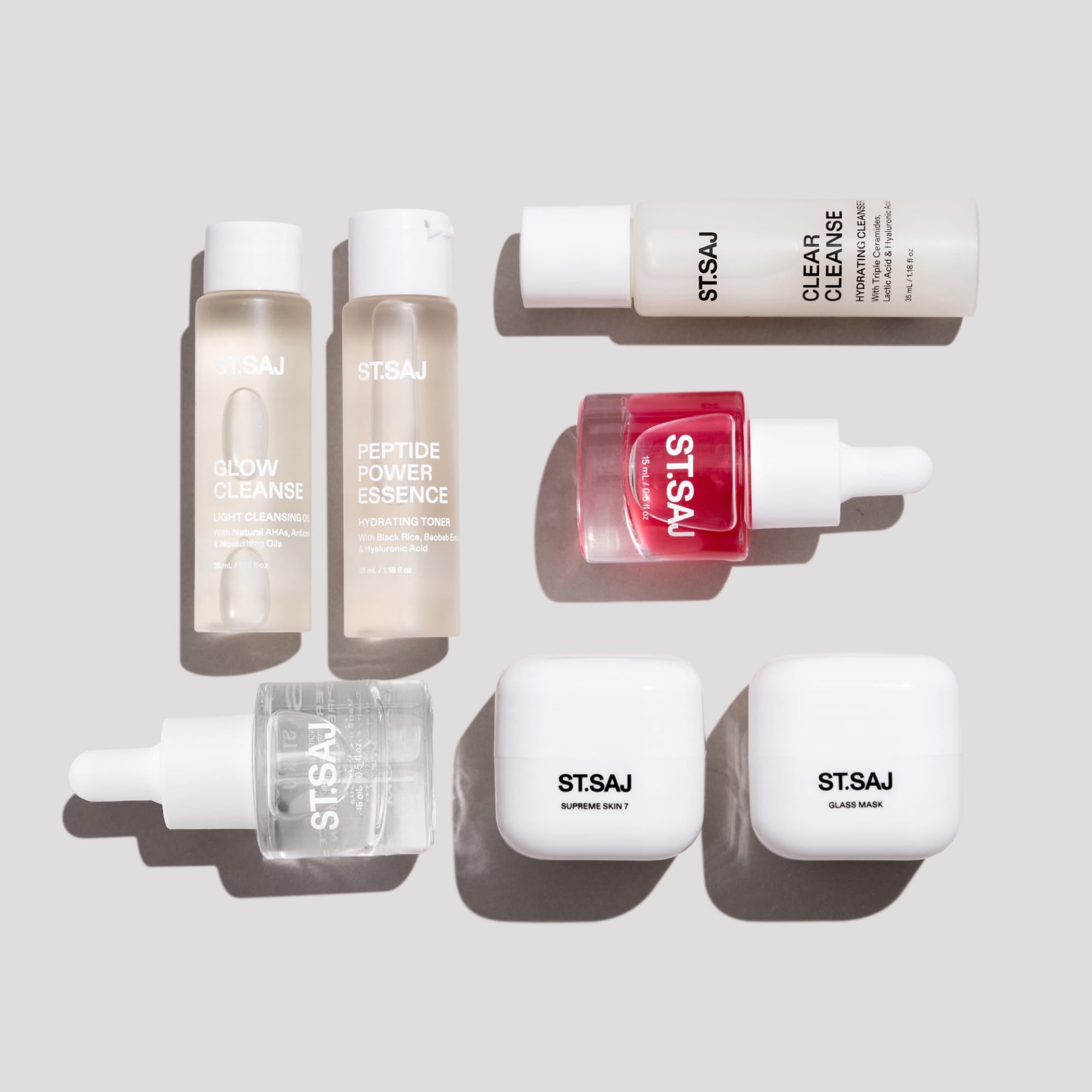 ST.SAJ On Tour Mini Kit - seven mini skincare products flat lay including Glow Cleanse, Clear Cleanse, NiaGlow Clarity Boost, Hyaluronic Smoothing Complex, Peptide Power Essence, Supreme Skin 7, Glass Mask