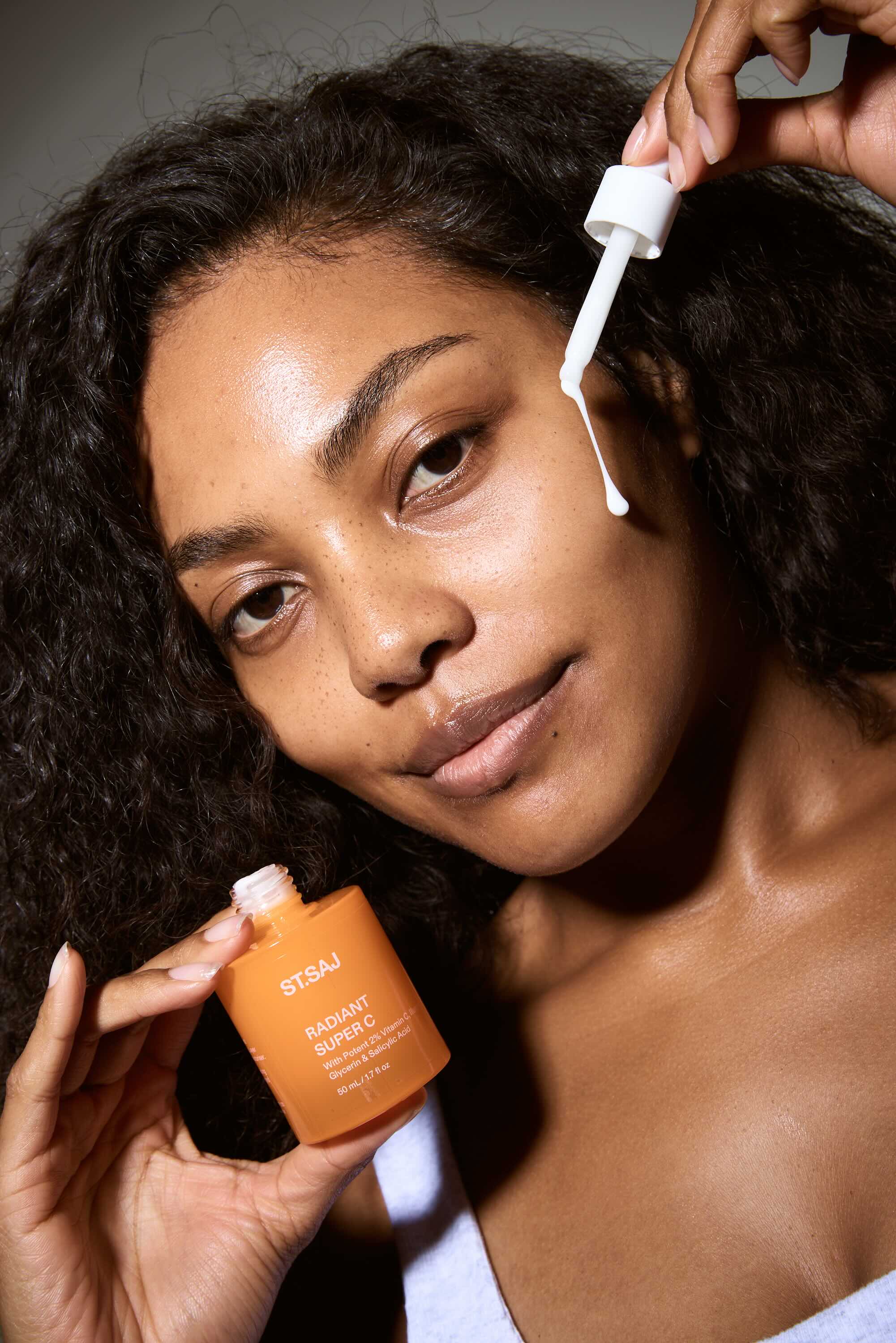 Woman applying skincare product to her face with a dropper bottle