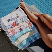 ST.SAJ Poolside Turkish Towel lifestyle shot - model poolside with ST.SAJ products