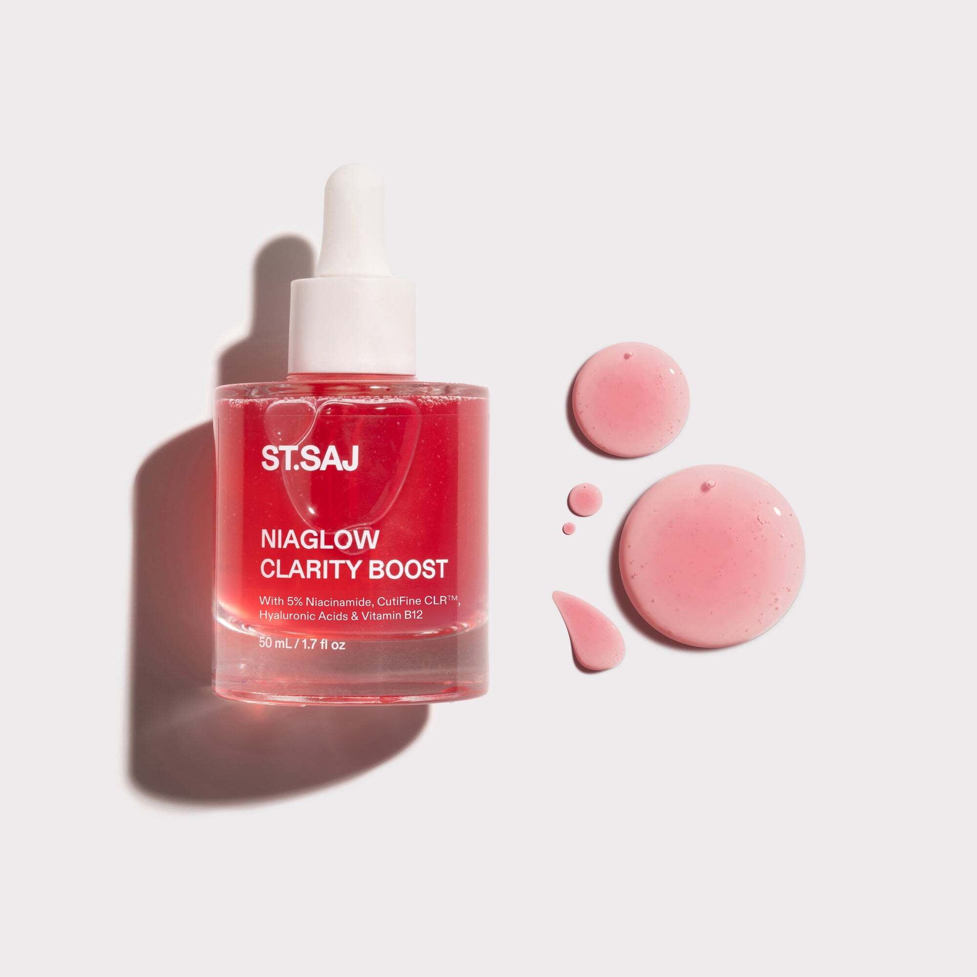 ST.SAJ Niaglow Clarity Boost serum bottle with pink product drops on a grey background