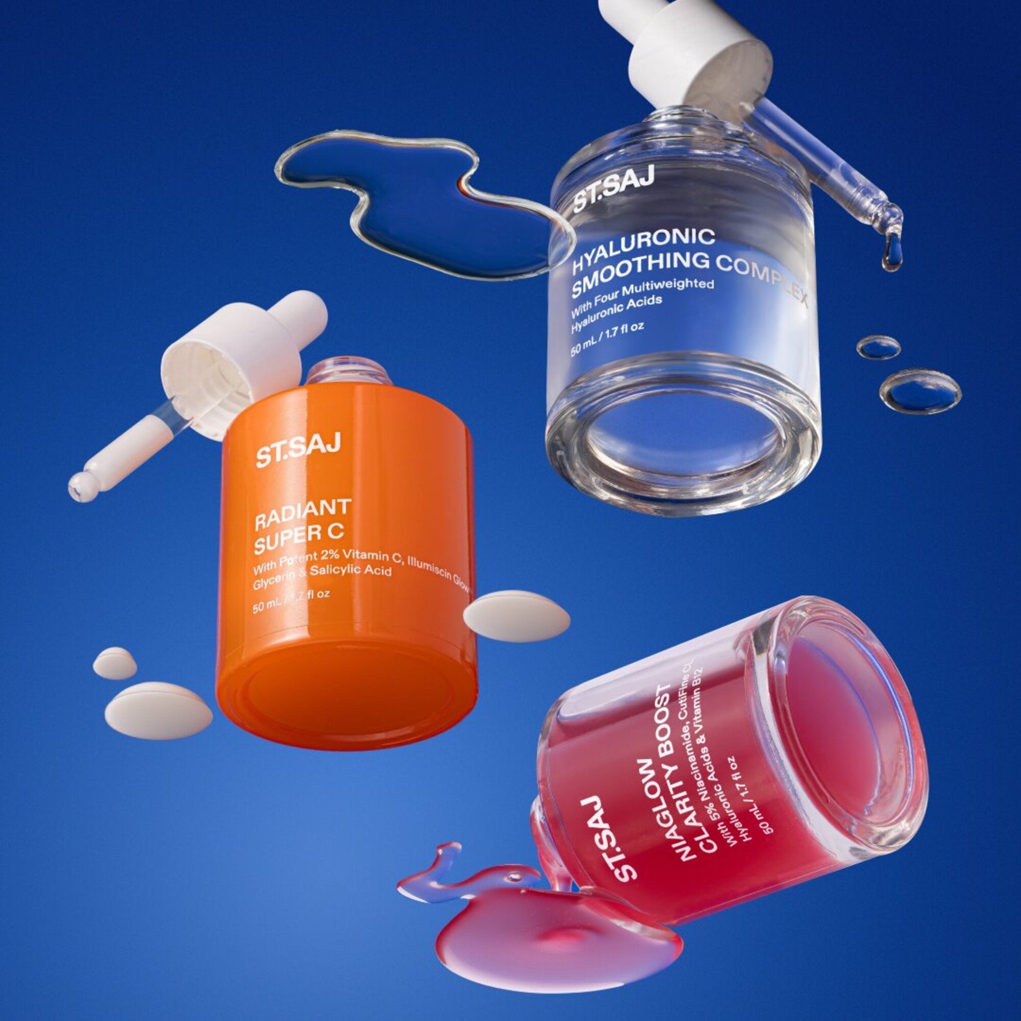 ST.SAJ Hyaluronic Smoothing Complex, Radiant Super C and Niaglow Clarity Boost serums floating on blue background with liquid splashes.