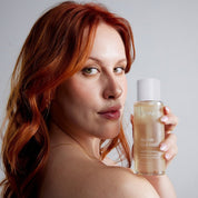 Red-haired woman holding ST.SAJ Glow Cleanse.