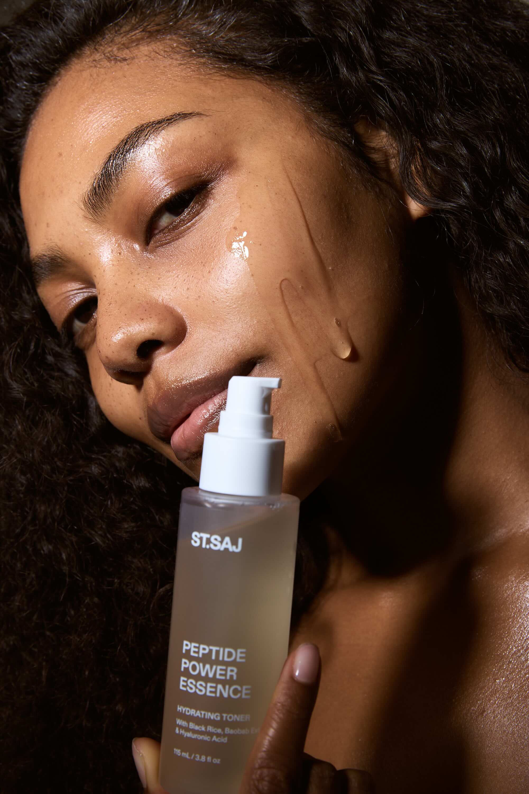 Person holding a bottle of STSAJ Peptide Power Essence with a close-up of their face.