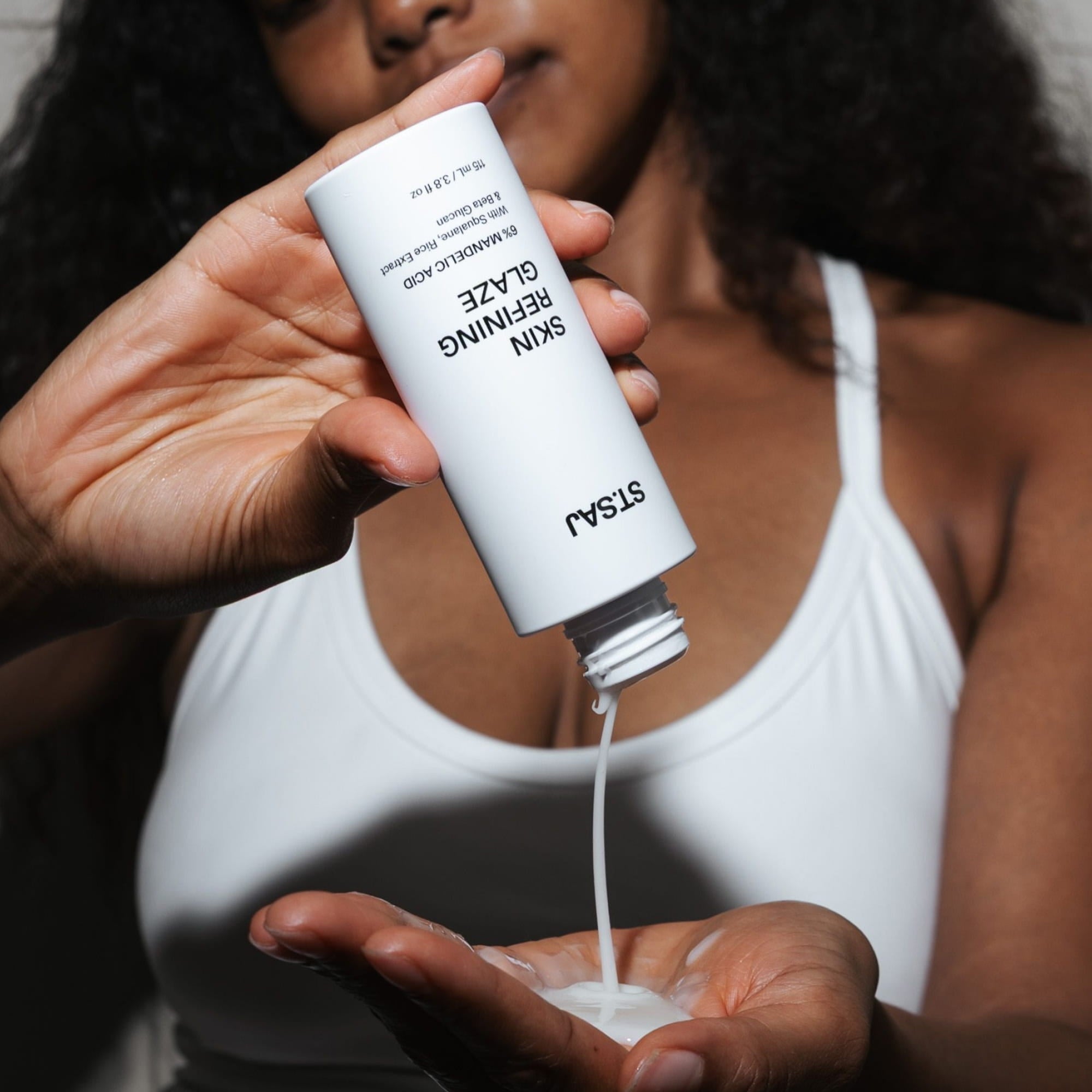 Woman pouring ST.SAJ Skin Refining Glaze into palm - mandelic acid exfoliant Australia