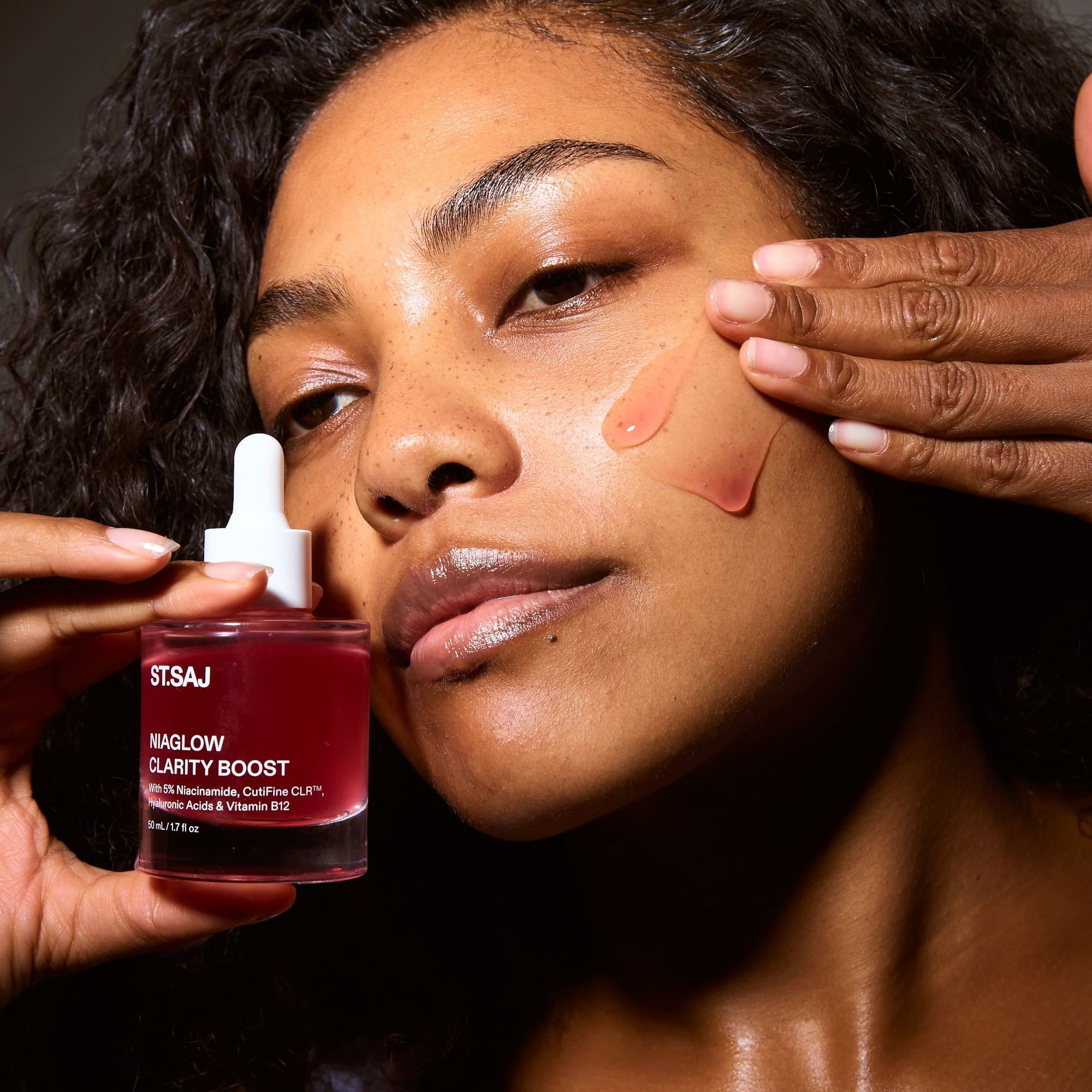 Woman holding ST.SAJ Niaglow Clarity Boost serum with a swatch